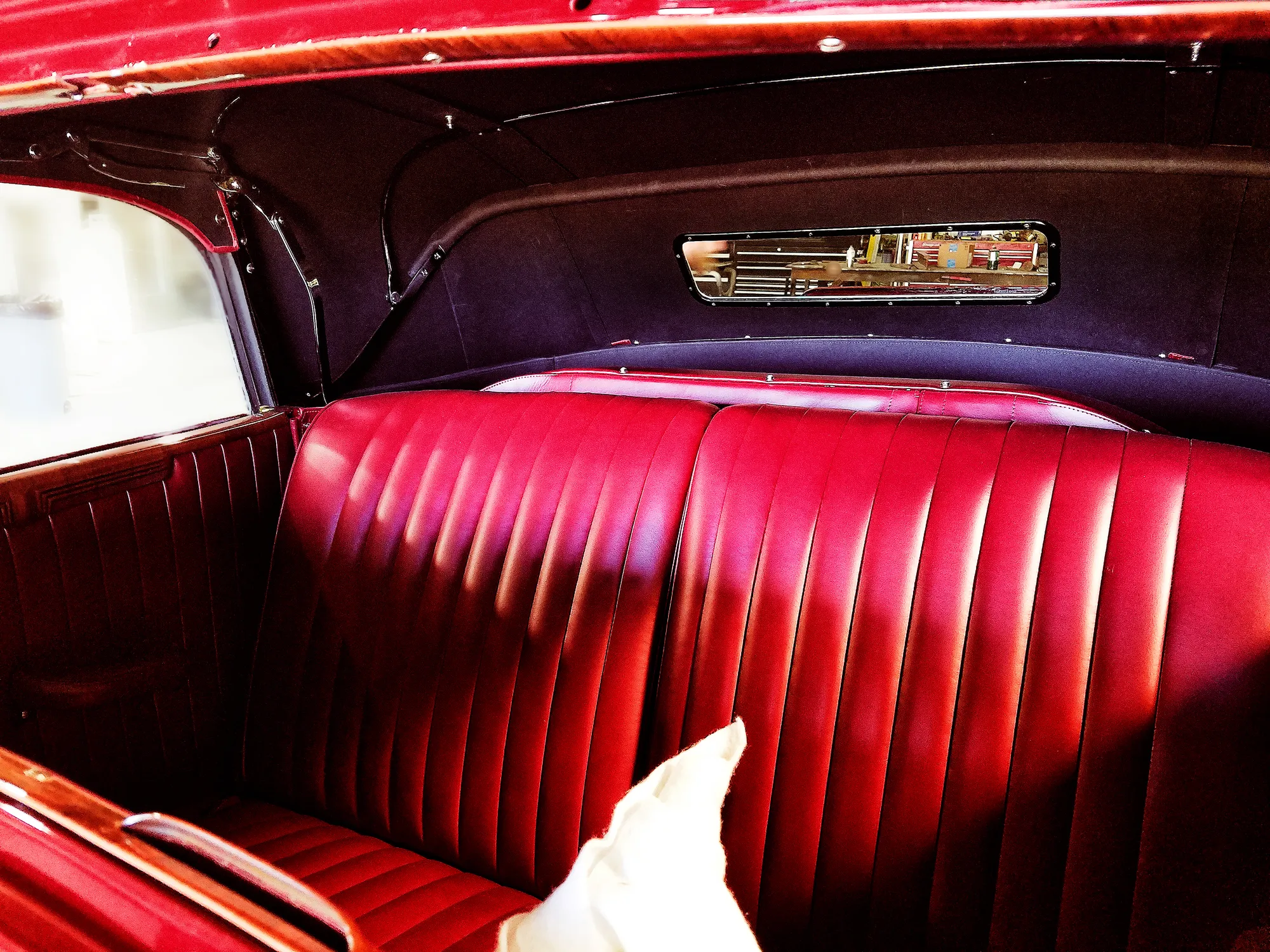 A red pleated rear bench seat and matching side panels under a dark convertible top.