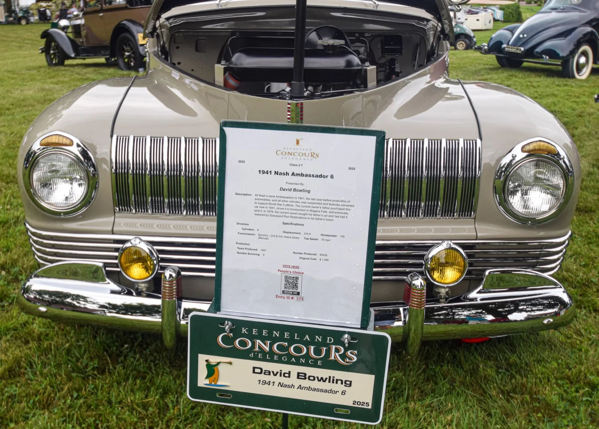 A tan 1941 Nash Ambassador 6 on a grass show field, hood raised, its Keeneland Concours d’Elegance placard in front of the grille.