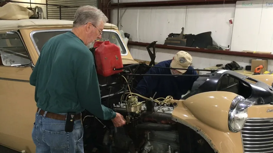 Black Betty, still beige, under the hood in the shop — a frame from build video #1.