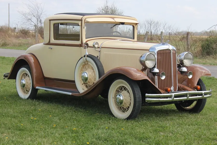 A cream vintage Packard-era sedan, three-quarter view.