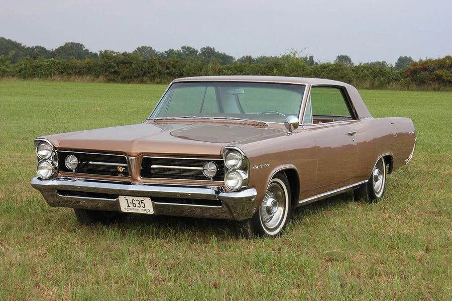 The restored 1963 Pontiac Grand Prix, front three-quarter on the grass.