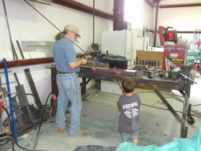A shop hand wet-sanding a classic body panel during show prep