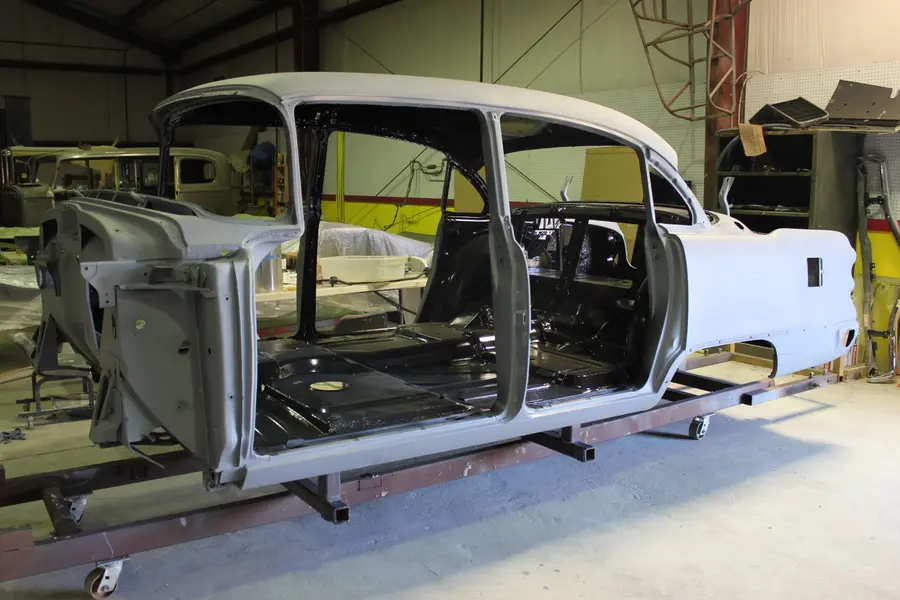 A stripped sedan body, bare panels against black interior paint.